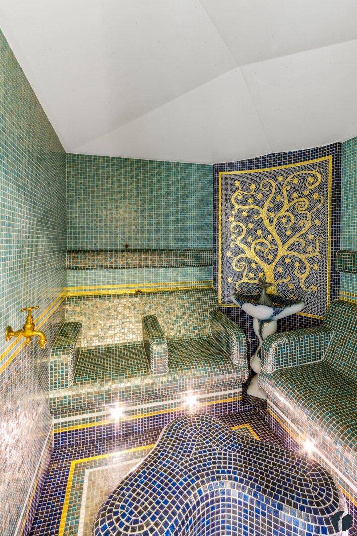 Exklusives Dampfbad mit farbenfrohen Mosaikfliesen und kunstvoller Wandgestaltung, ideal zur Entspannung.