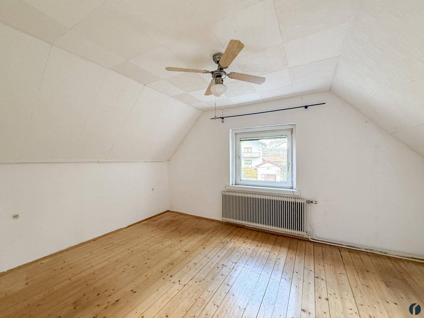Helles Schlafzimmer im Dachgeschoss mit Holzdielenboden und Dachschräge, ideal für Ruhe.