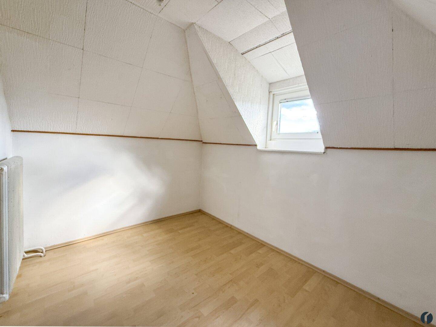 Kleiner Raum im Dachgeschoss mit Dachfenster und Holzboden, bietet viel Tageslicht.