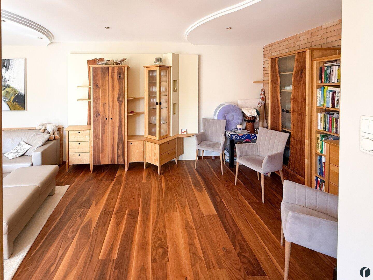 Geräumiges Wohnzimmer mit Holzboden, Bücherregalen und dekorativen Holzschränken.