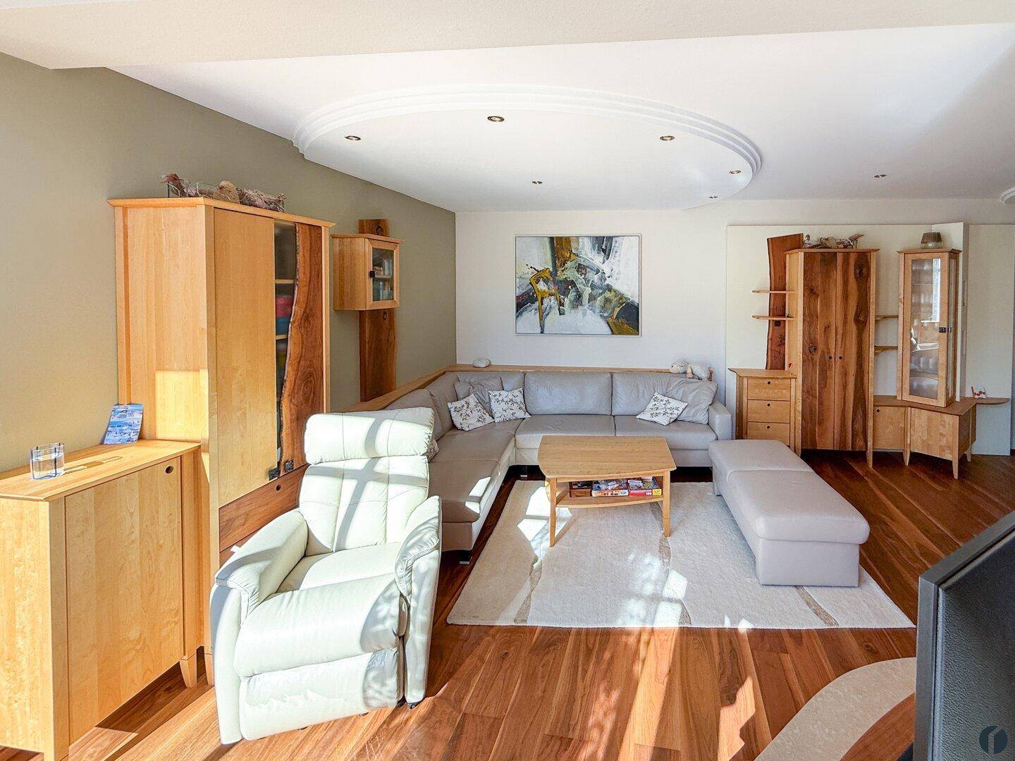 Helles Wohnzimmer mit Holzboden, bequemer Sofalandschaft und eleganten Holzmöbeln.