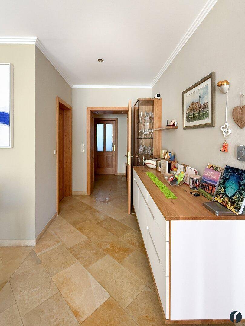 Heller Flur mit beigefarbenen Fliesen, modernem Sideboard und Holztüren.