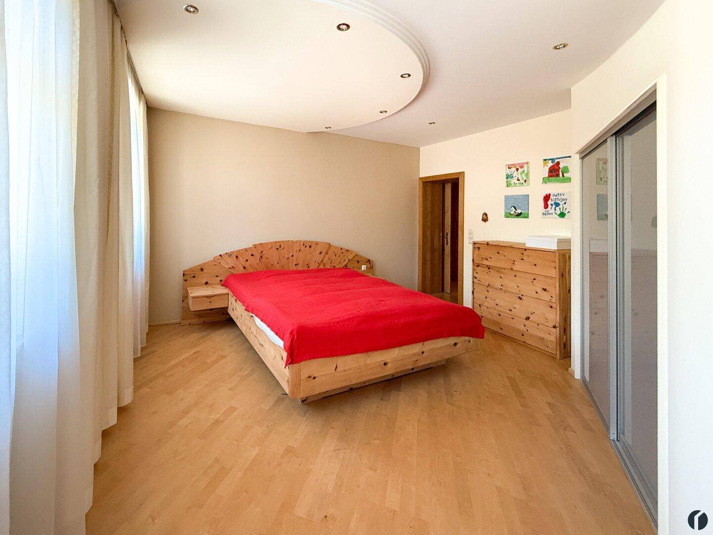 Gemütliches Schlafzimmer mit Holzboden, Holzbett und Kommode, hell und freundlich.