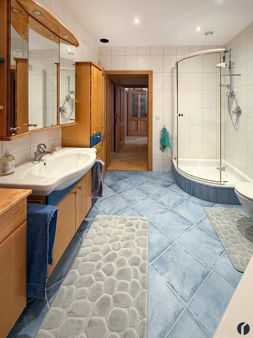 Funktionelles Badezimmer mit Waschbecken, Spiegelschrank und Duschkabine.