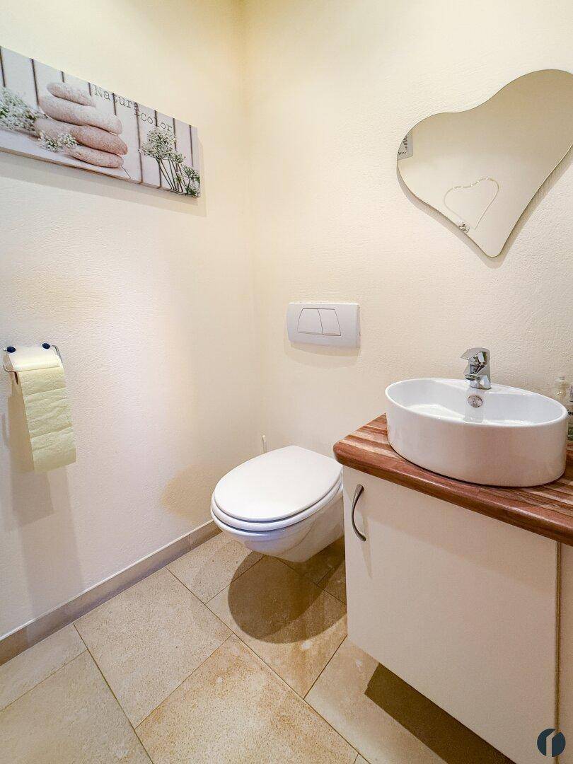 Modernes Gäste-WC mit wandhängendem WC, Aufsatzwaschbecken und Herzspiegel.