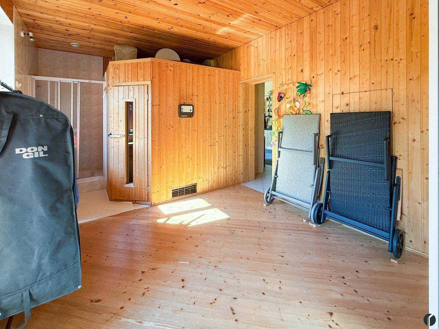 Gemütlicher Wellnessbereich mit Holzverkleidung, Sauna und angrenzender Dusche.