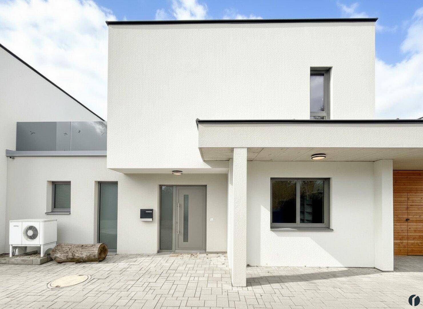 Moderne Hausfassade mit klaren Linien, großen Fenstern und einladendem Eingangsbereich.