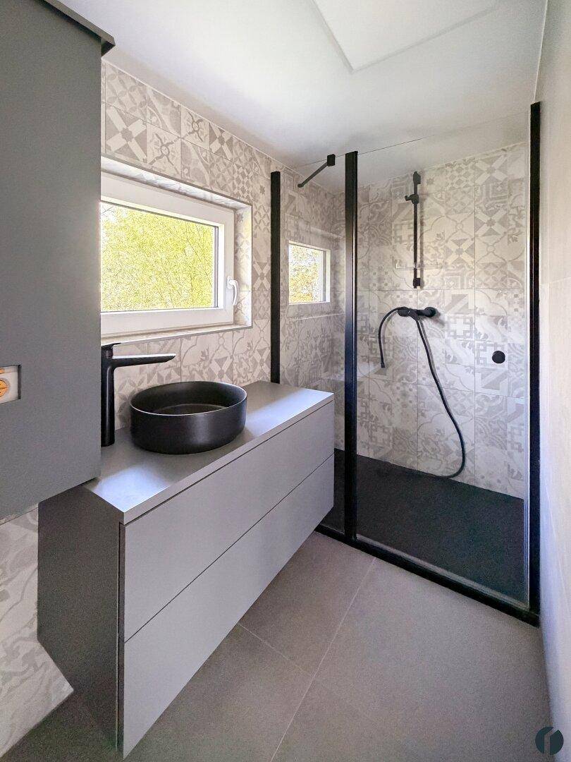 Modernes Badezimmer mit begehbarer Dusche, stilvollen Fliesen und Fenster für Tageslicht.