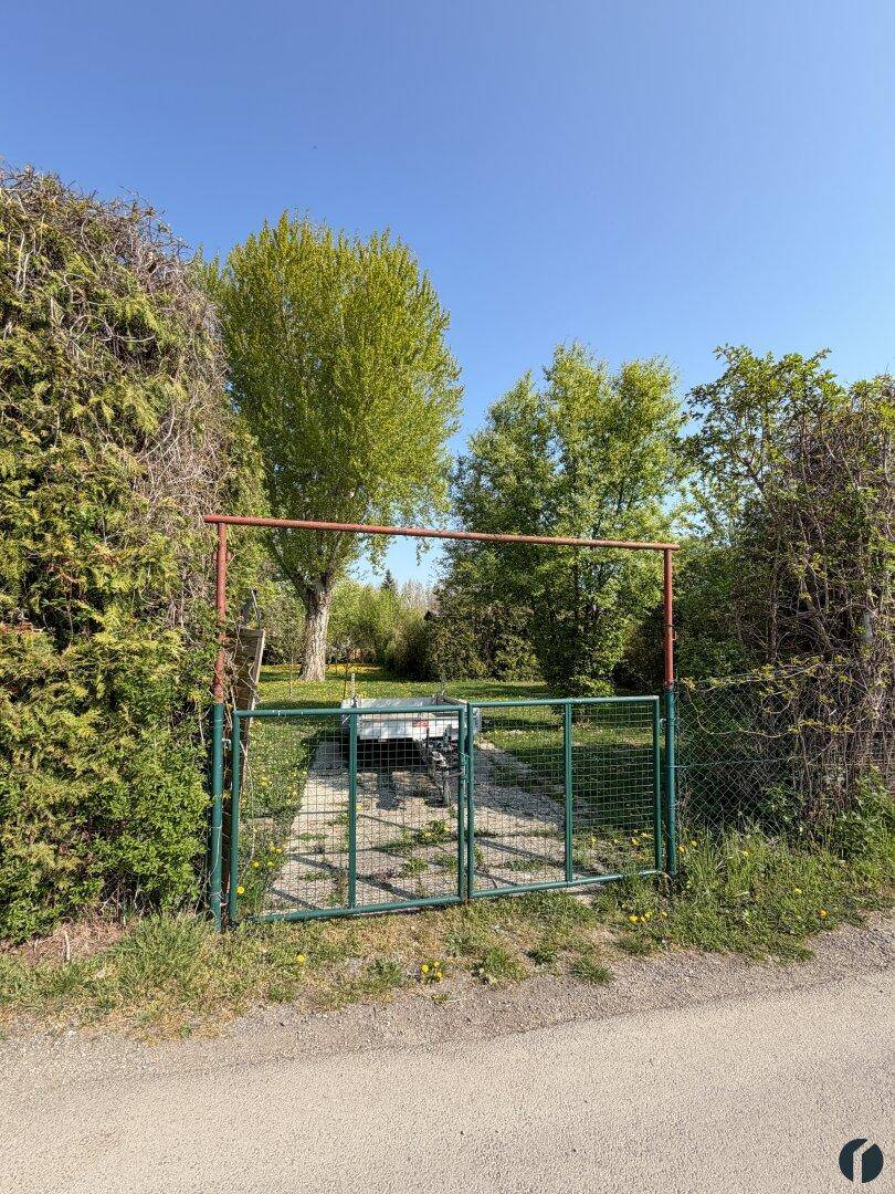 Einfahrt zum Grundstück mit Metalltor und umgebender Hecke, die Privatsphäre bietet.