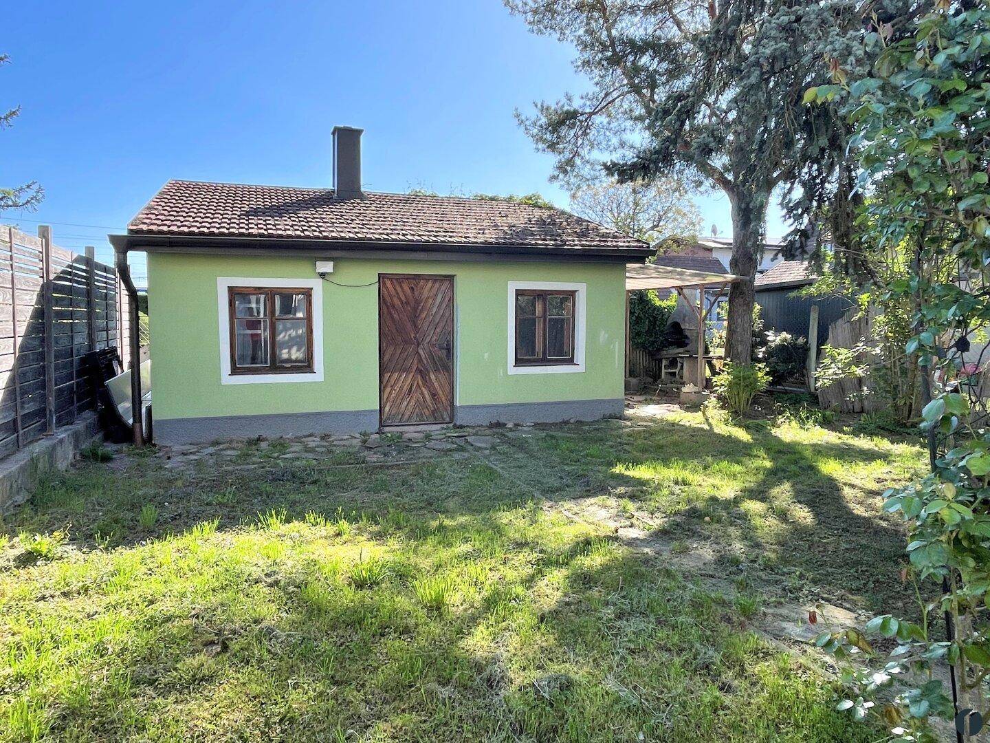 Seitenansicht des Hauses mit grüner Fassade und einem gepflegten Gartenbereich.