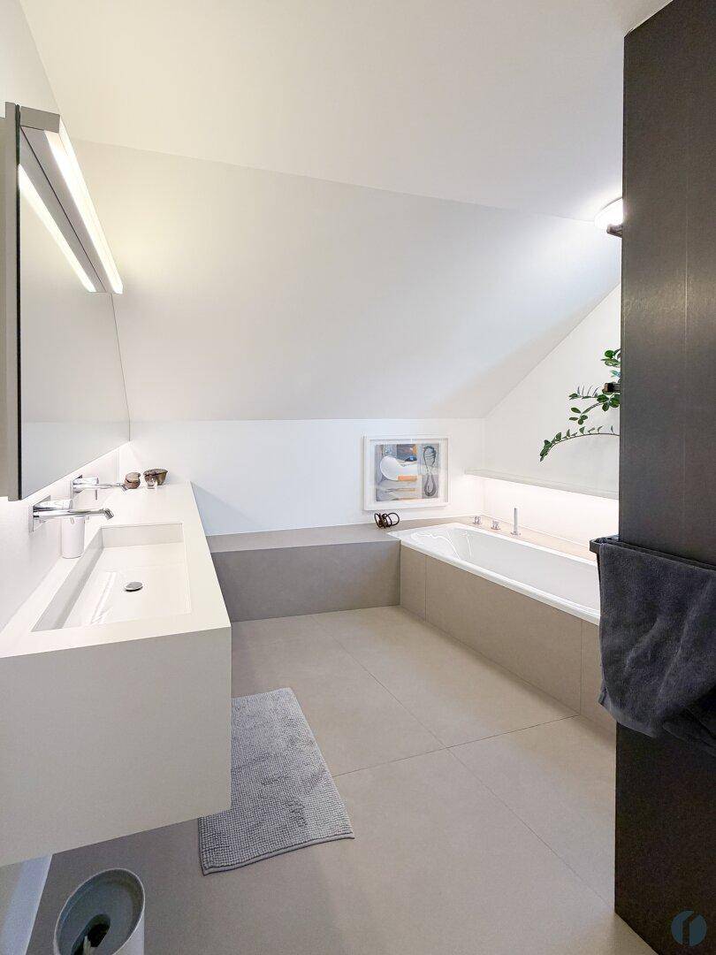 Modernes Badezimmer im Dachgeschoss mit Doppelwaschbecken, Badewanne und schrägen Wänden.