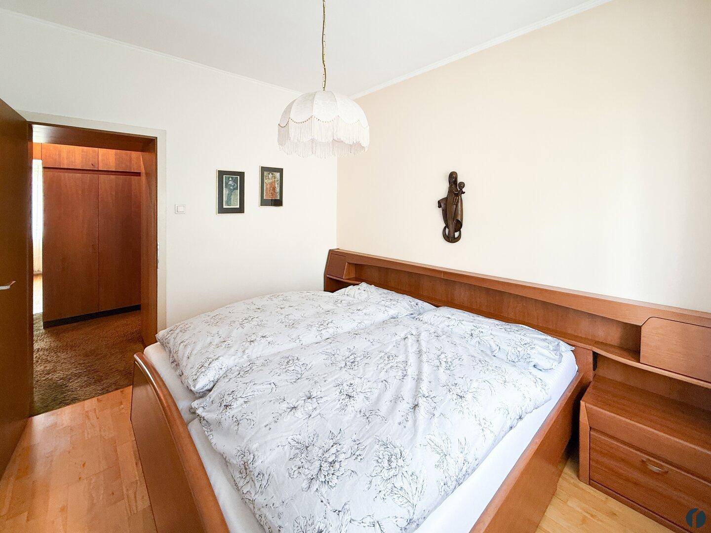 Schlafzimmer mit Doppelbett, Holzmöbeln und traditioneller Einrichtung.