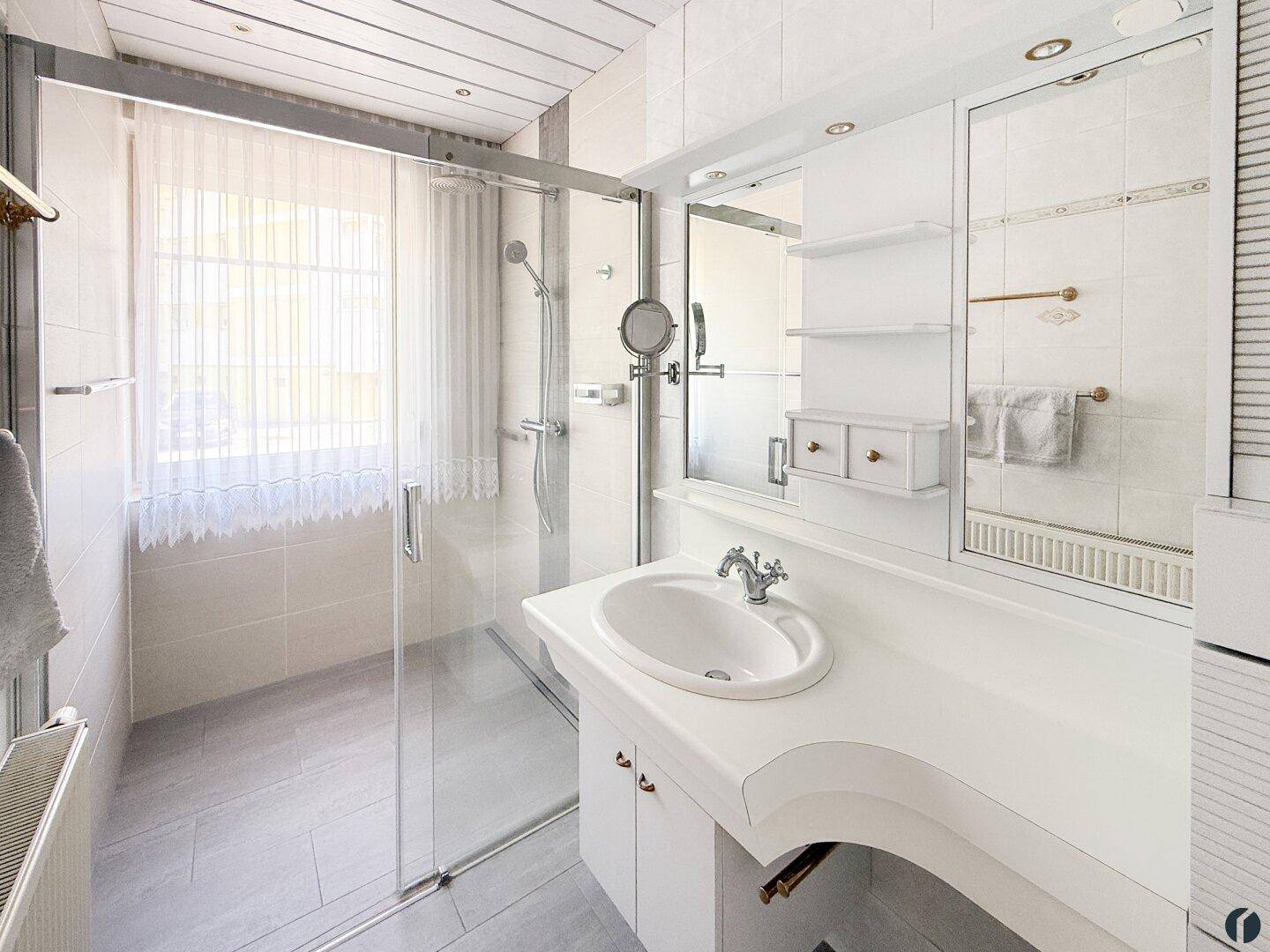 Helles Badezimmer mit Duschkabine, Einzelwaschbecken und Fenster für Tageslicht.