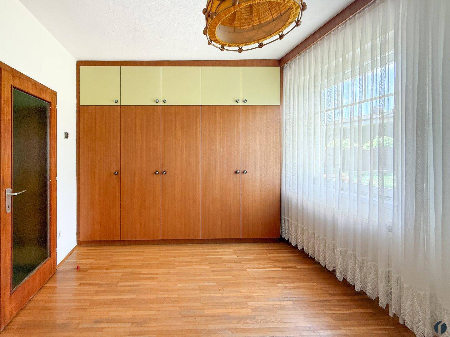 Raum mit großen Einbauschränken aus Holz und einem Fenster für natürliches Licht.