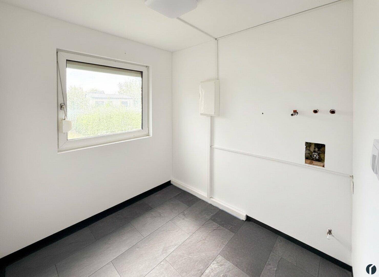 Kleiner Raum mit Fenster und Anschlüssen, ideal als Hauswirtschaftsraum nutzbar.