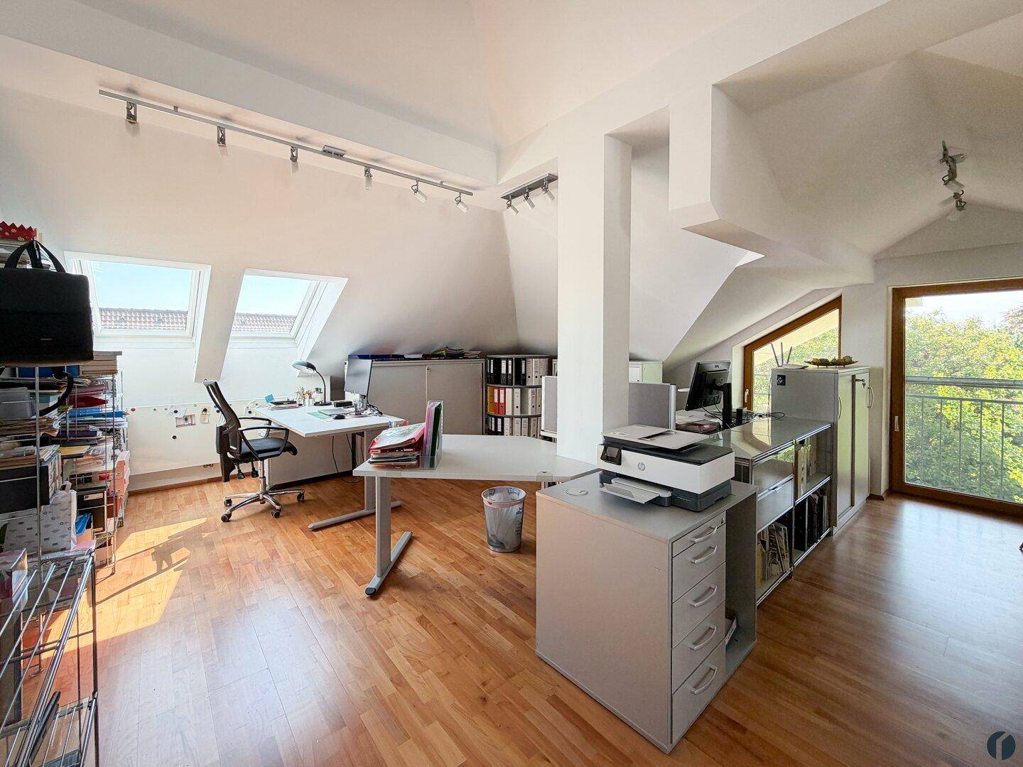 Helles Dachgeschossbüro mit Holzboden, Dachfenstern und Zugang zum Balkon.