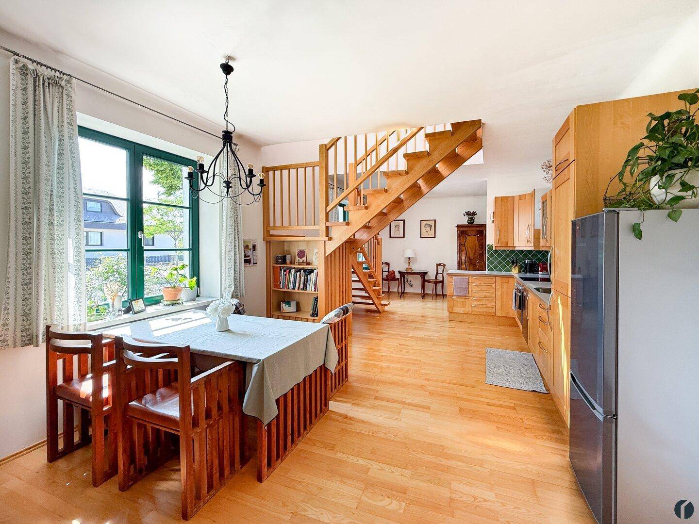 Offener Wohn-Essbereich mit Holzboden, Esstisch und Treppe zum Obergeschoss.