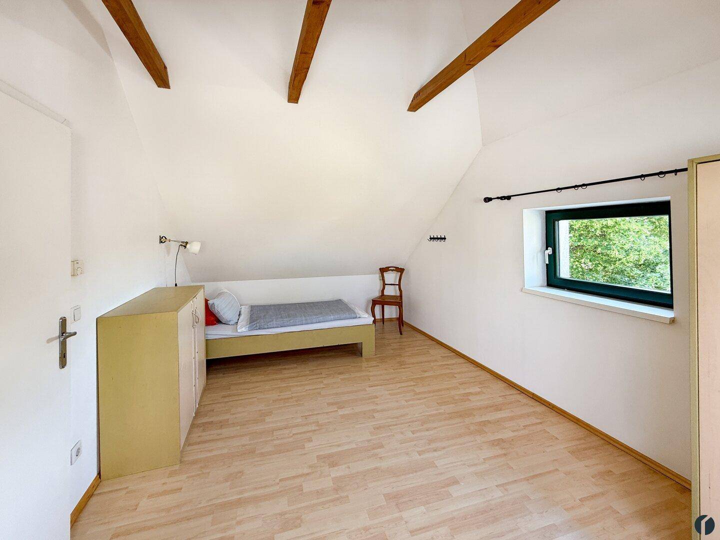 Kleines Schlafzimmer im Dachgeschoss mit Einzelbett, Holzbalken und Fenster.