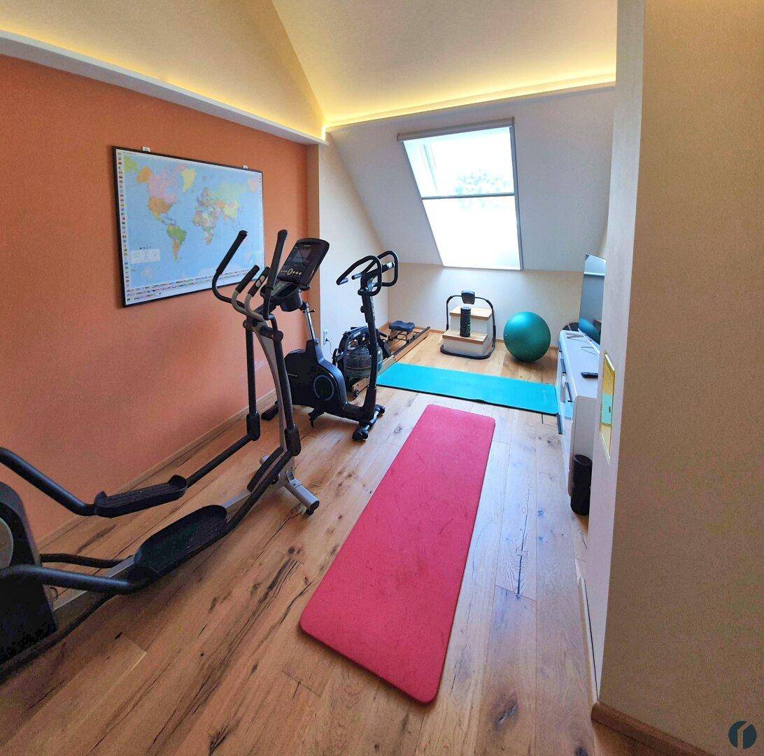 Fitnessraum im Dachgeschoss mit Trainingsgeräten, Schrägdach und Dachfenster.