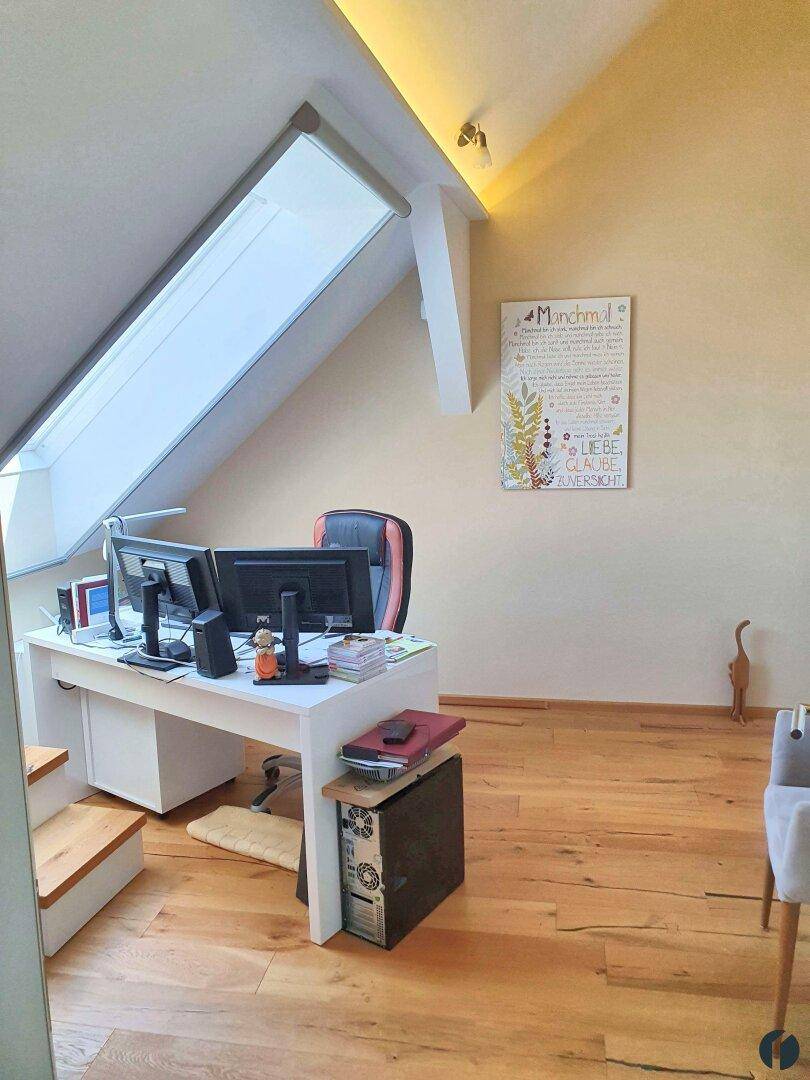 Helles Büro im Dachgeschoss mit Holzboden und großem Dachfenster für viel Tageslicht.