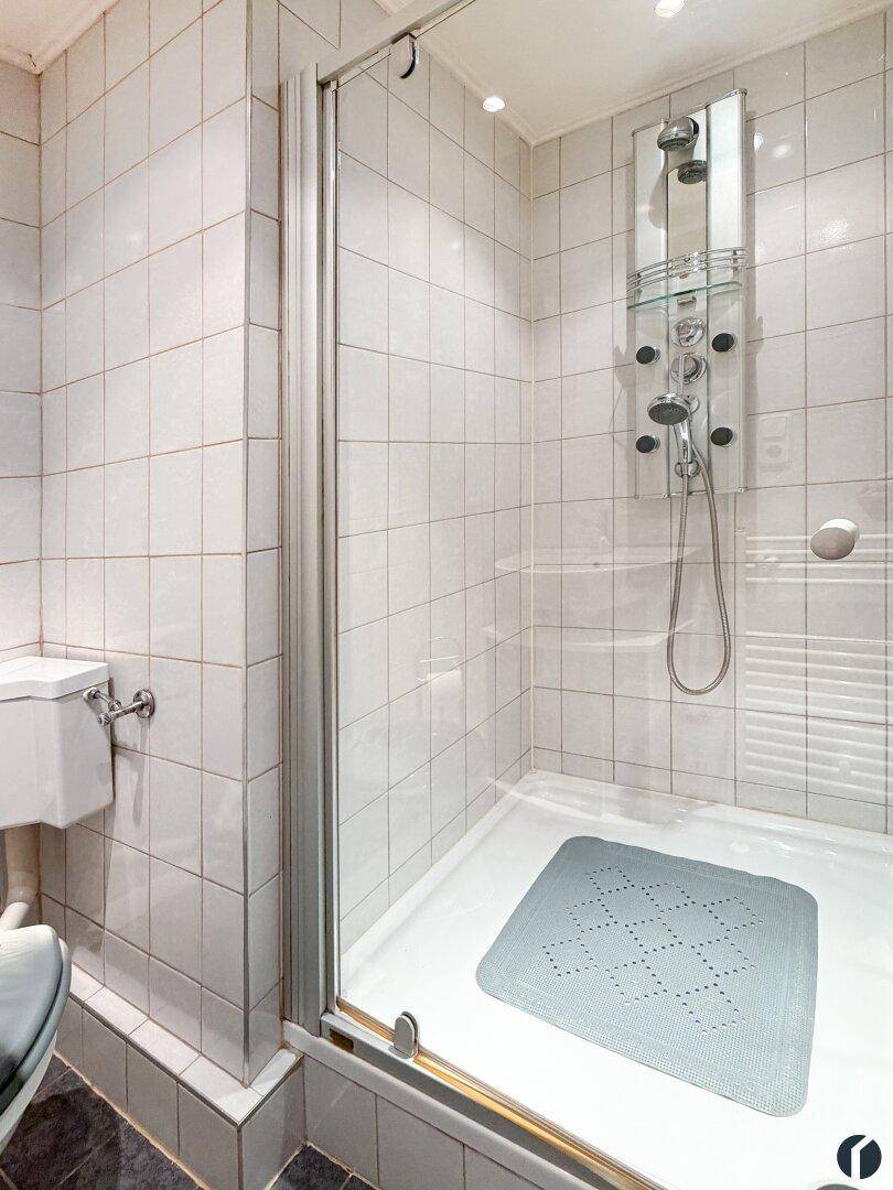 Duschbereich im Badezimmer mit Glasabtrennung und moderner Duscharmatur.