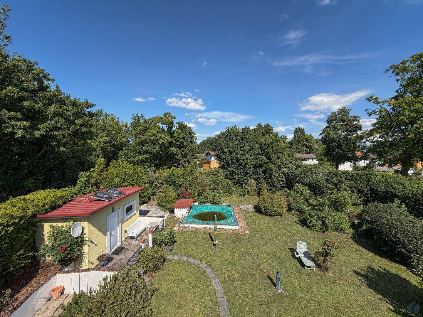Weitläufiger Gartenbereich mit Pool, Gartenhaus und üppiger grüner Umgebung.