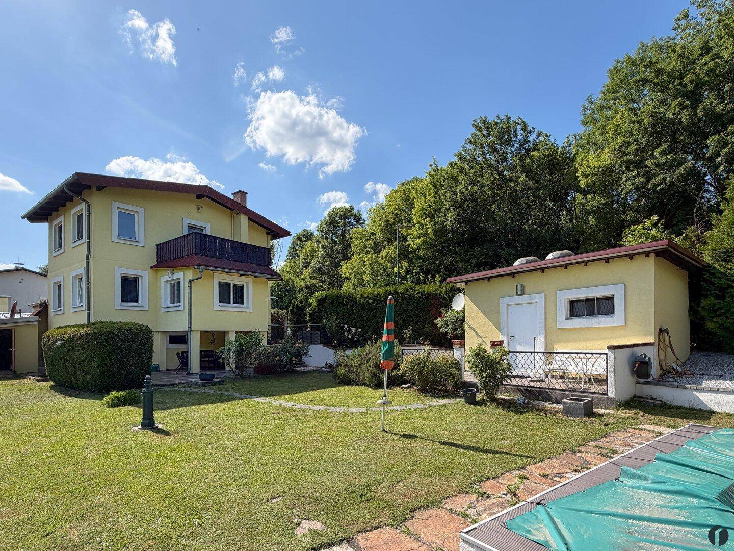 Ansicht des Hauses und des Gartenhauses mit Pool und weitläufigem Rasenbereich.