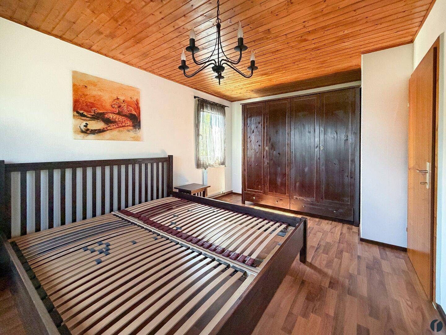 Geräumiges Schlafzimmer mit Holzbettrahmen, großem Kleiderschrank und Holzdecke.