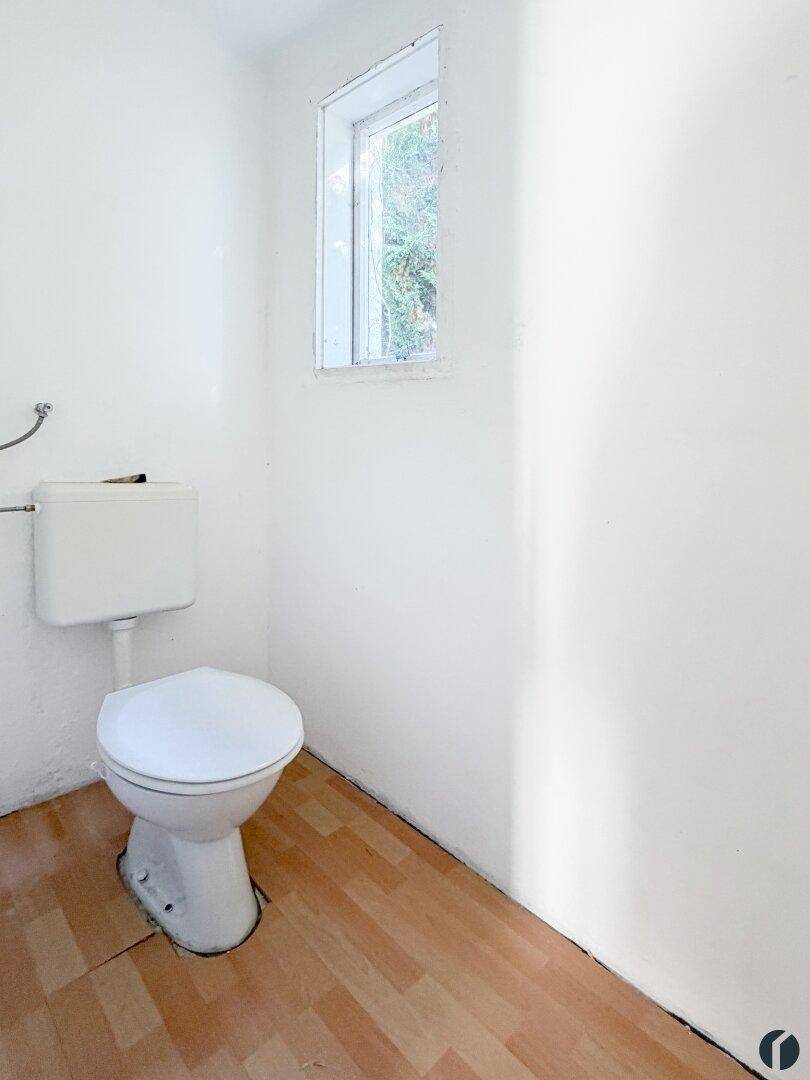 Einfaches Gäste-WC mit Fenster und Steh-WC, bereit für eine Modernisierung.