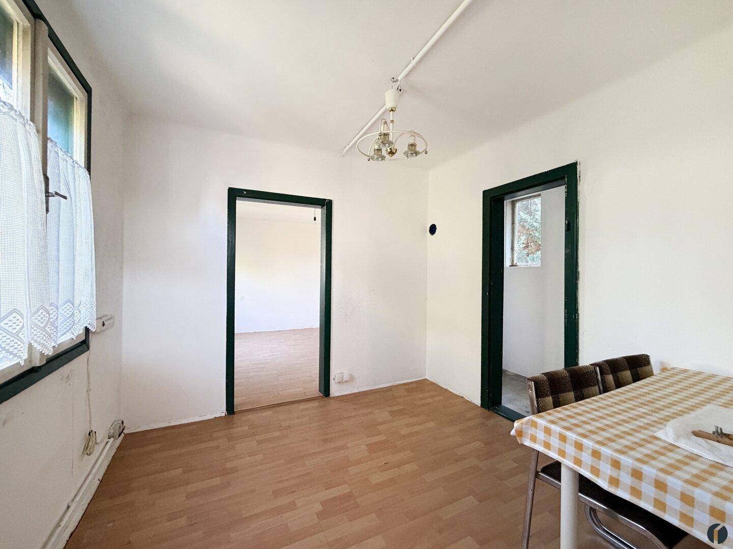 Geräumiges Esszimmer mit Laminatboden und Blick durch die Tür in einen weiteren Raum.
