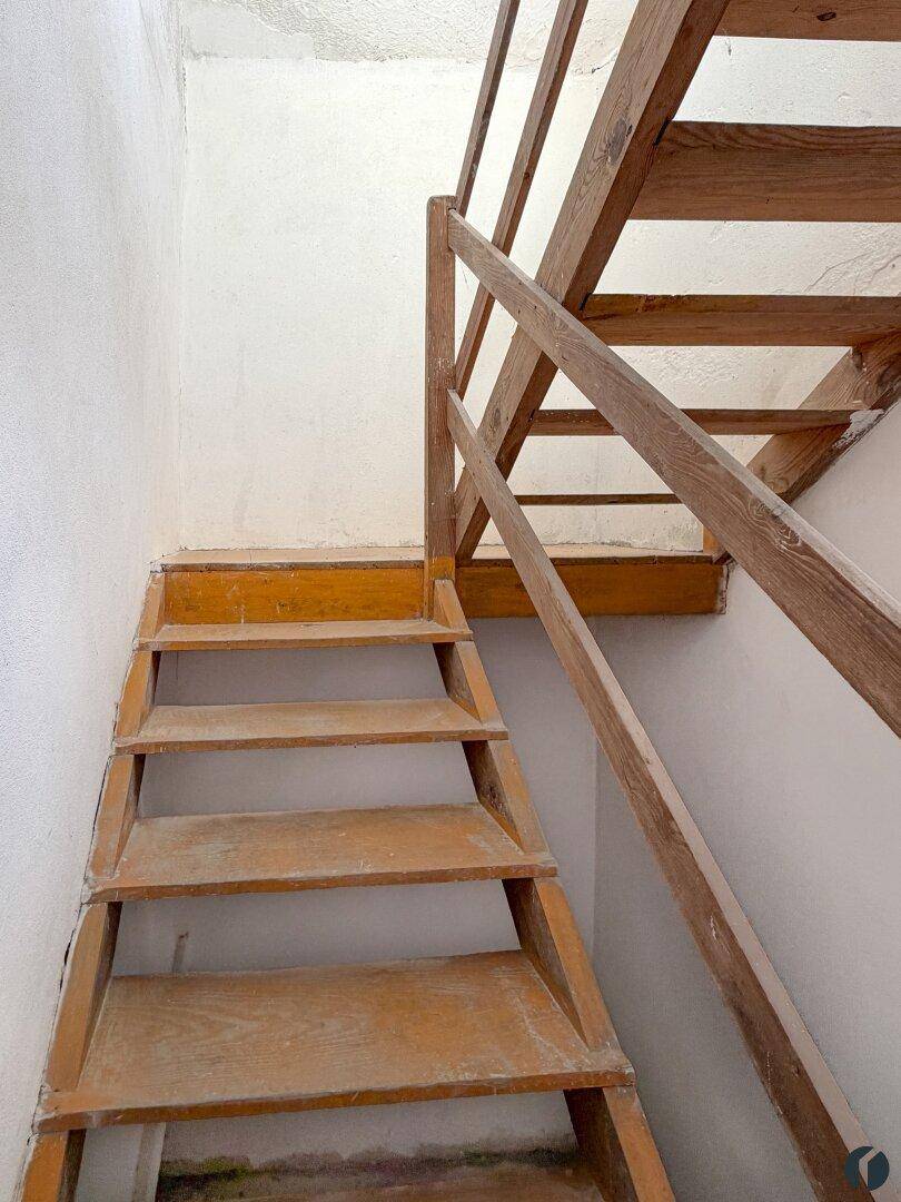 Rustikale Holztreppe mit Geländer, die in ein oberes Stockwerk führt.