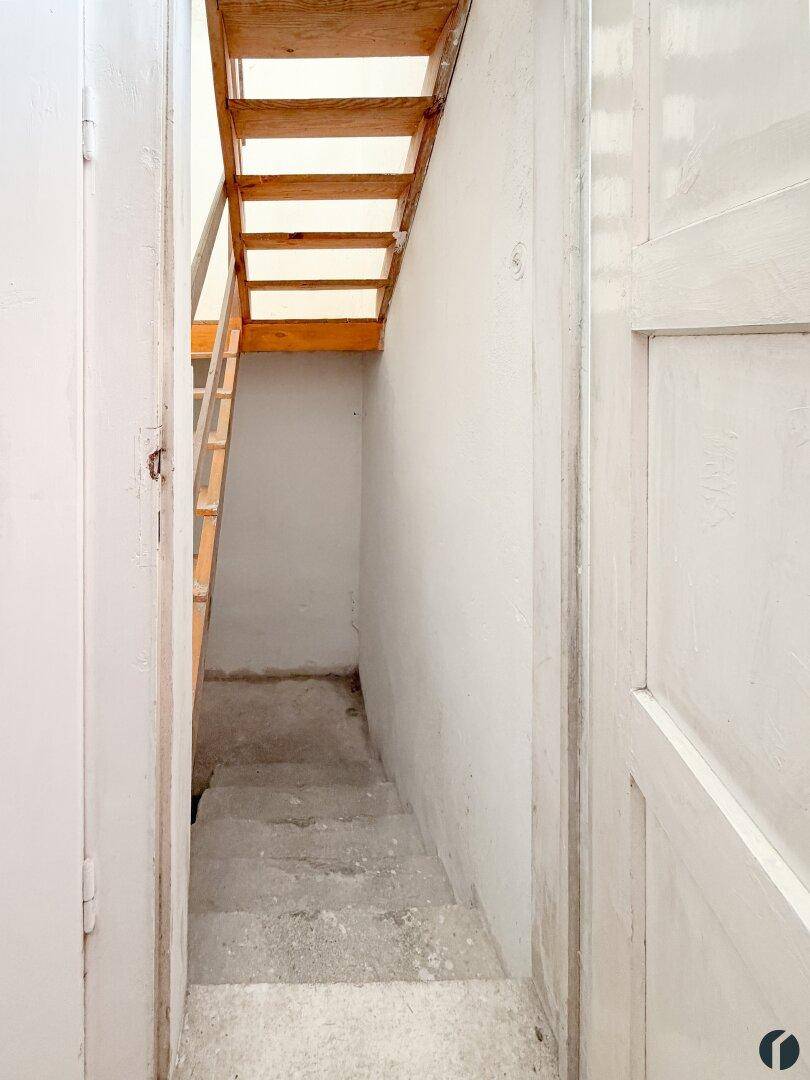 Schmaler Treppenabgang mit Holzstufen, der in den Kellerbereich führt.