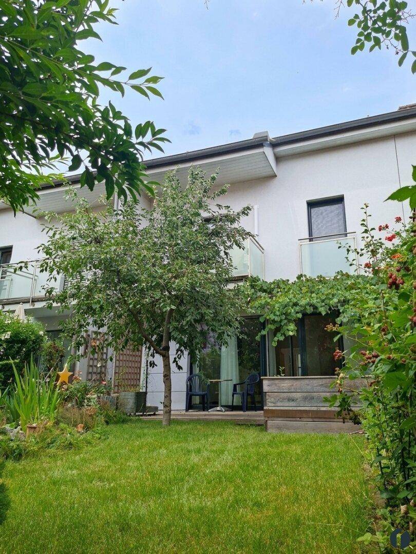 Reihenhaus mit Balkonen und gepflegtem Garten mit Rasenfläche.
