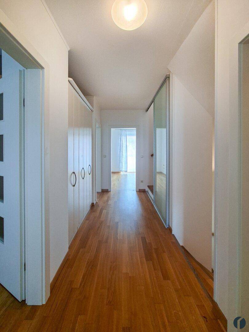 Langer, heller Flur mit Holzparkettboden und Einbauschränken.