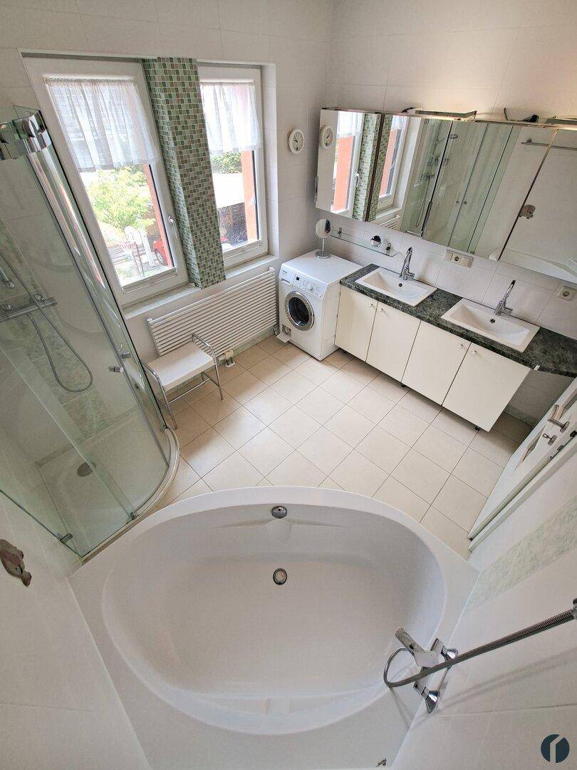 Geräumiges Badezimmer mit Badewanne, Dusche, Doppelwaschbecken und Fenster.