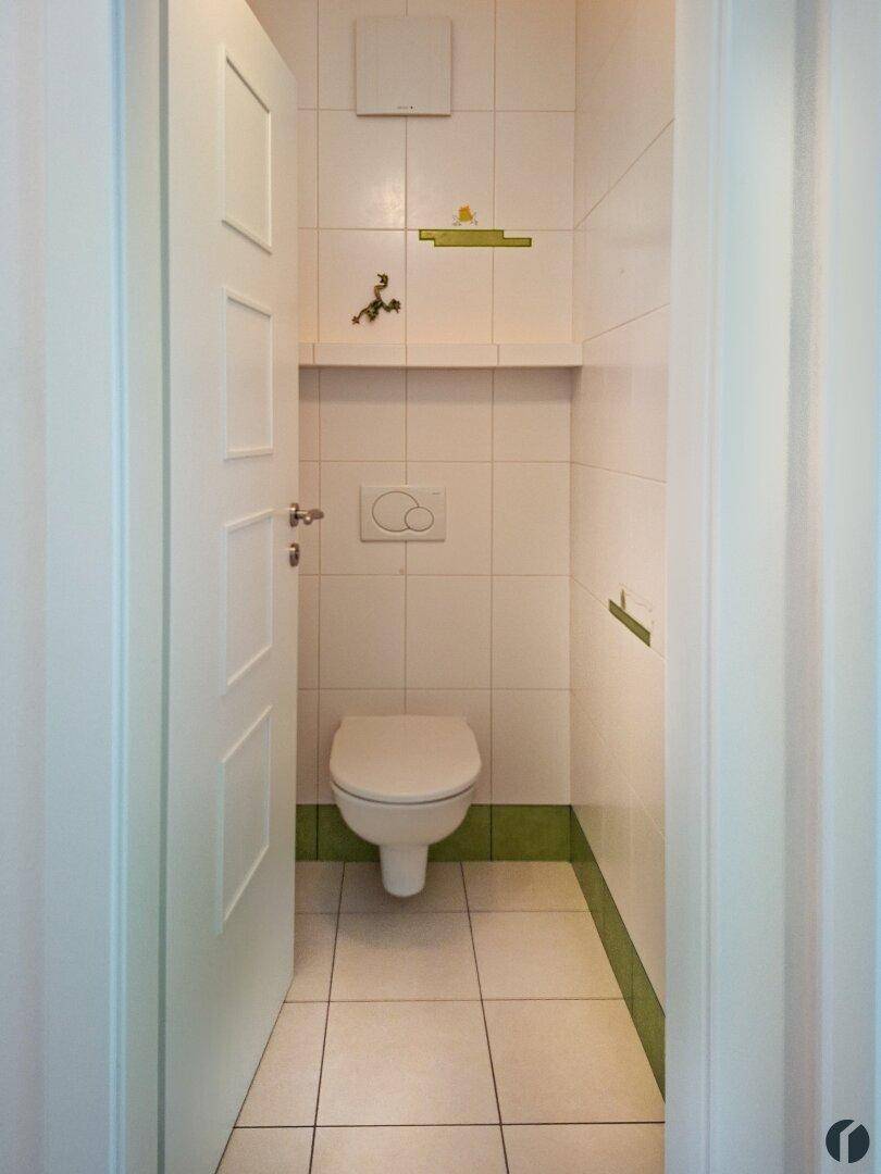 Kleines Gäste-WC mit weißen Fliesen und Wand-WC.