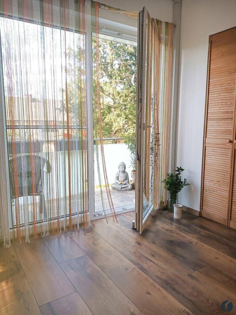 Schlafzimmer mit Holzboden und direktem Zugang zu einem Außenbereich, dekoriert mit einer Buddha-Statue.