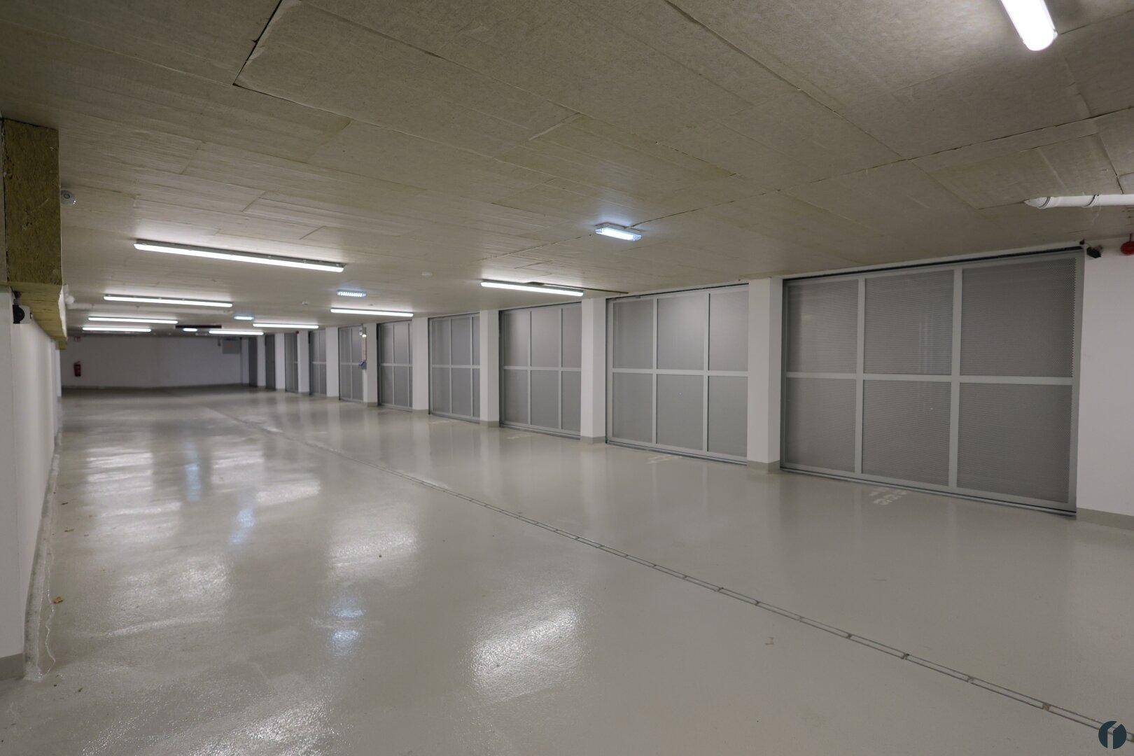 Tiefgarage mit mehreren Stellplätzen und Zugang zu den Kellerabteilen.
