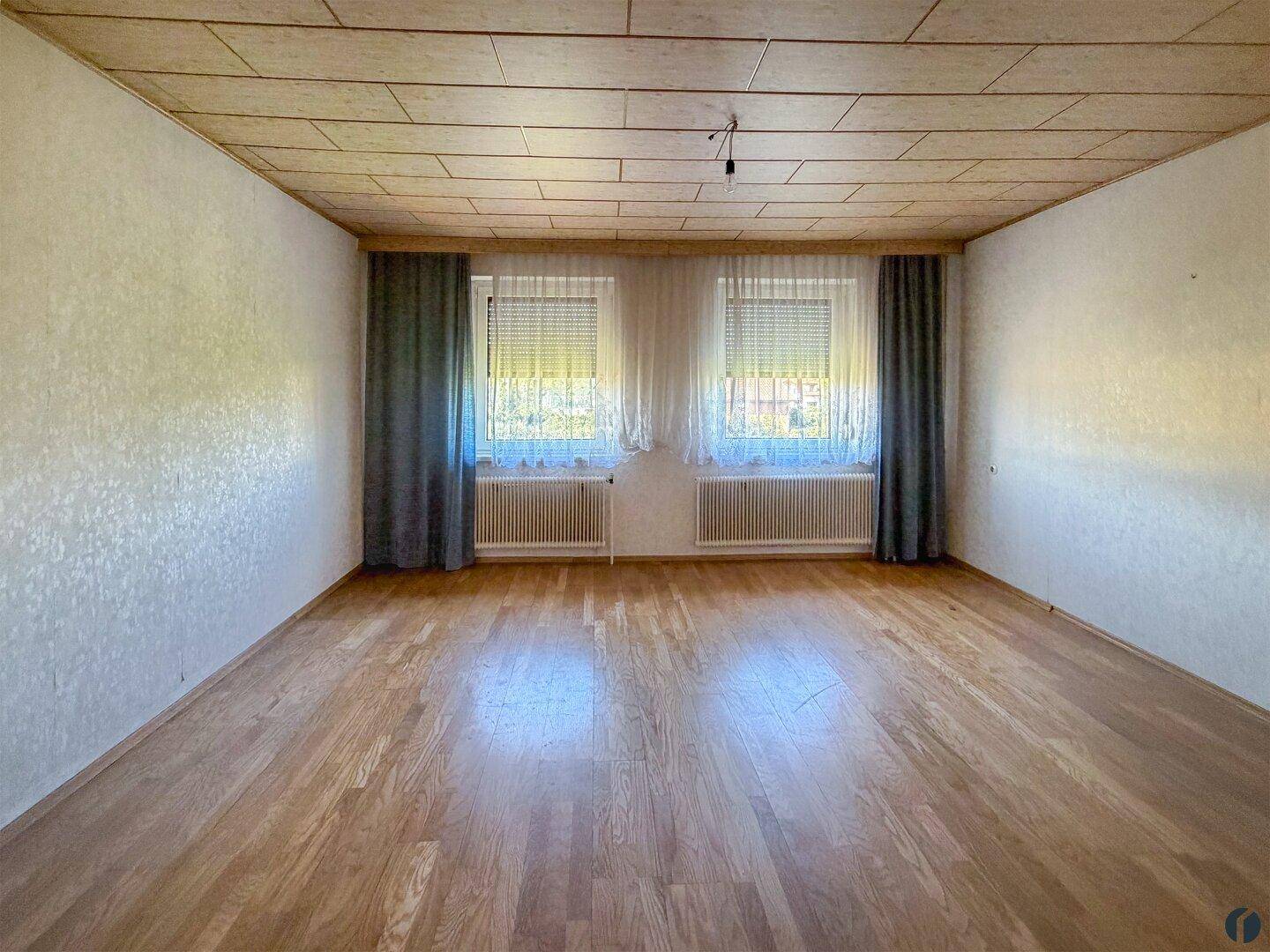 Geräumiges Wohnzimmer mit hellem Laminatboden und Holzdecke, bereit zur individuellen Gestaltung.