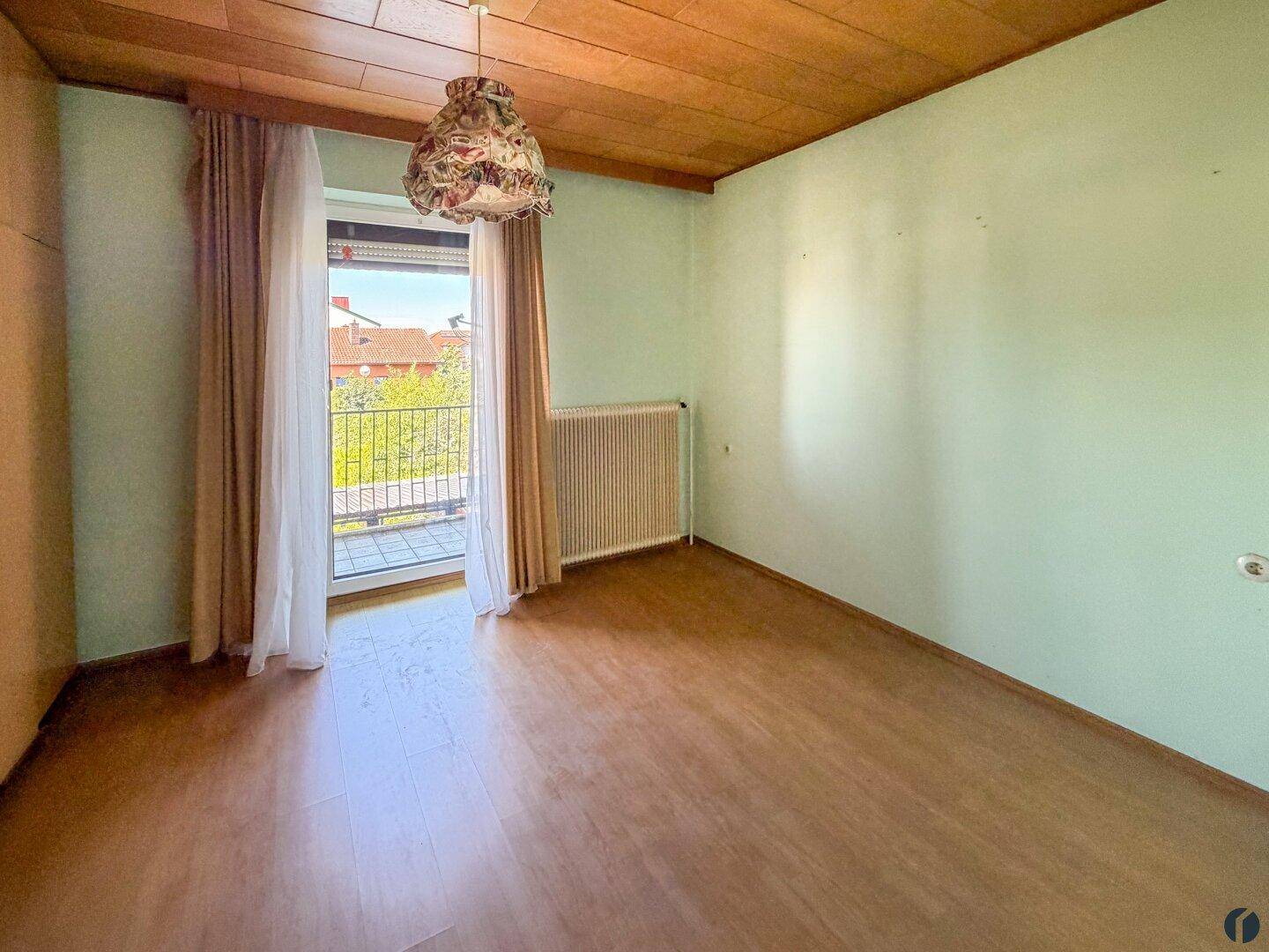 Schlafzimmer mit Laminatboden, Holzdecke und Zugang zu einem Balkon mit Aussicht.