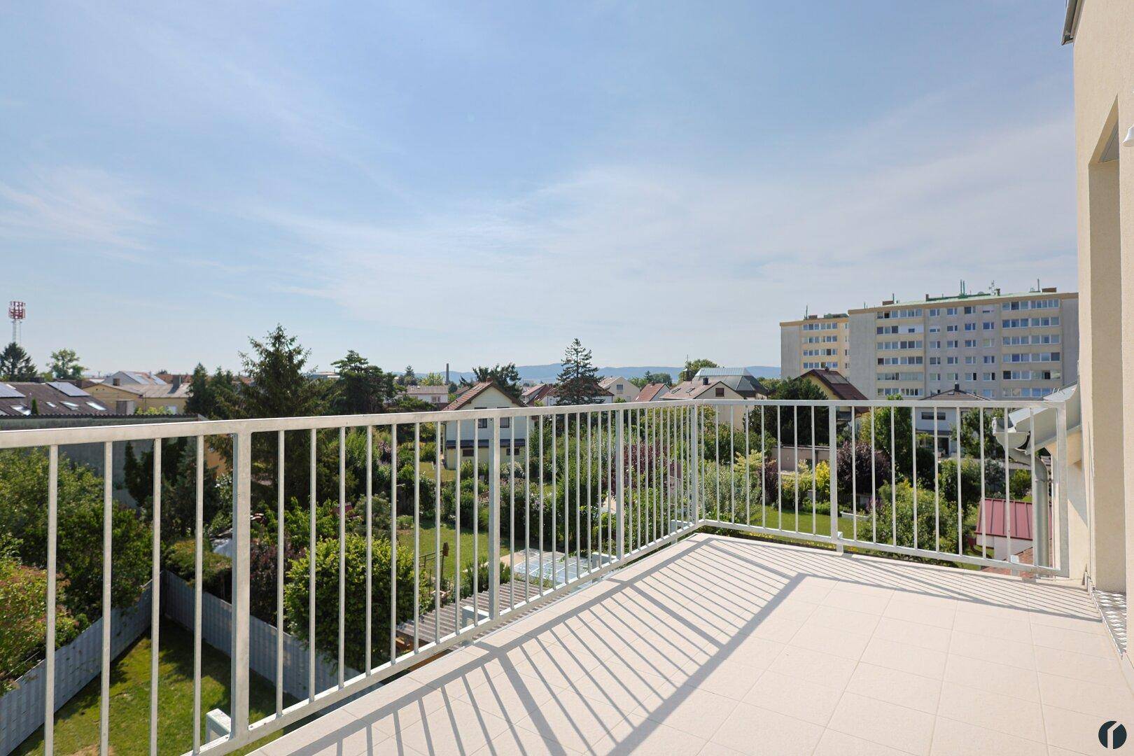Großer Balkon mit Fliesenboden und weitem Blick über die grüne Nachbarschaft.