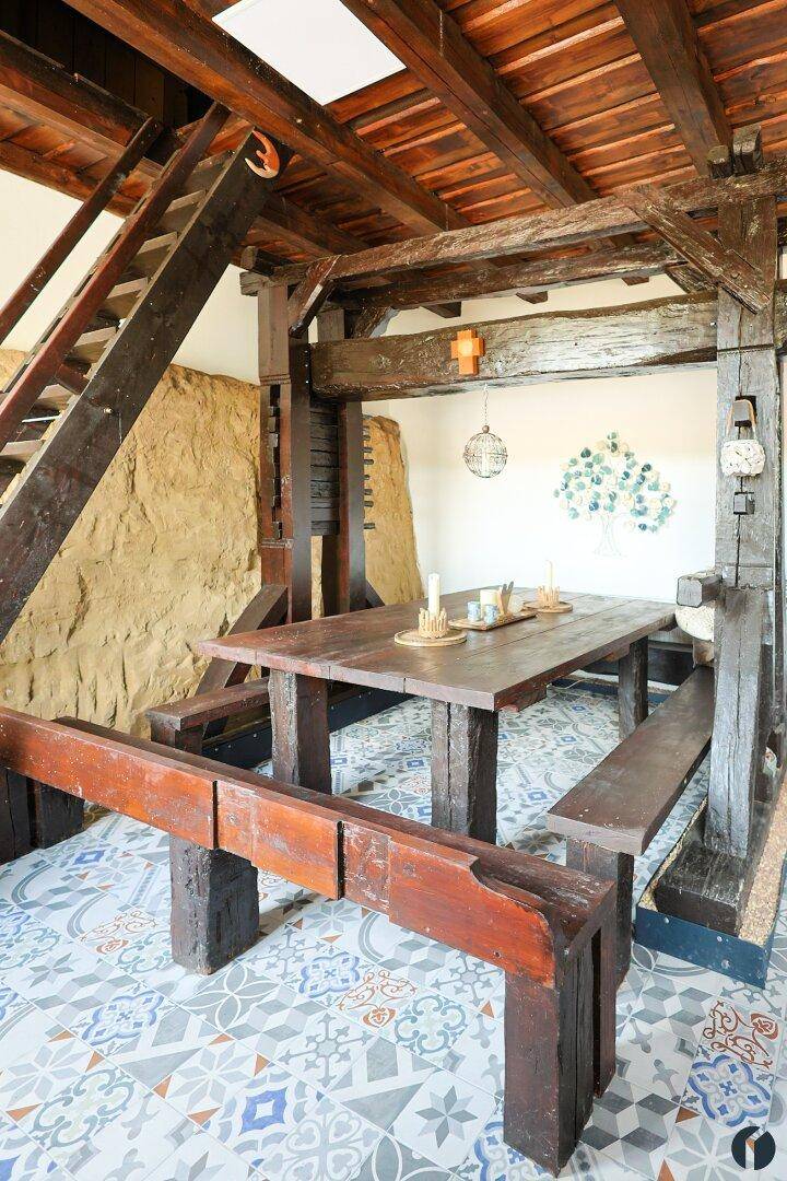 Geräumiger Wohn- und Essbereich mit massiven Holzbalken und einer rustikalen Holztreppe.
