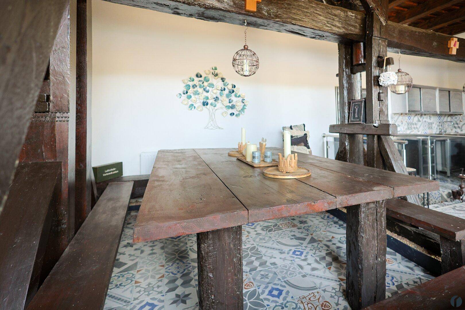 Rustikaler Holztisch mit Bänken im Wohnbereich, umgeben von farbenfrohen Fliesen und Wanddekoration.