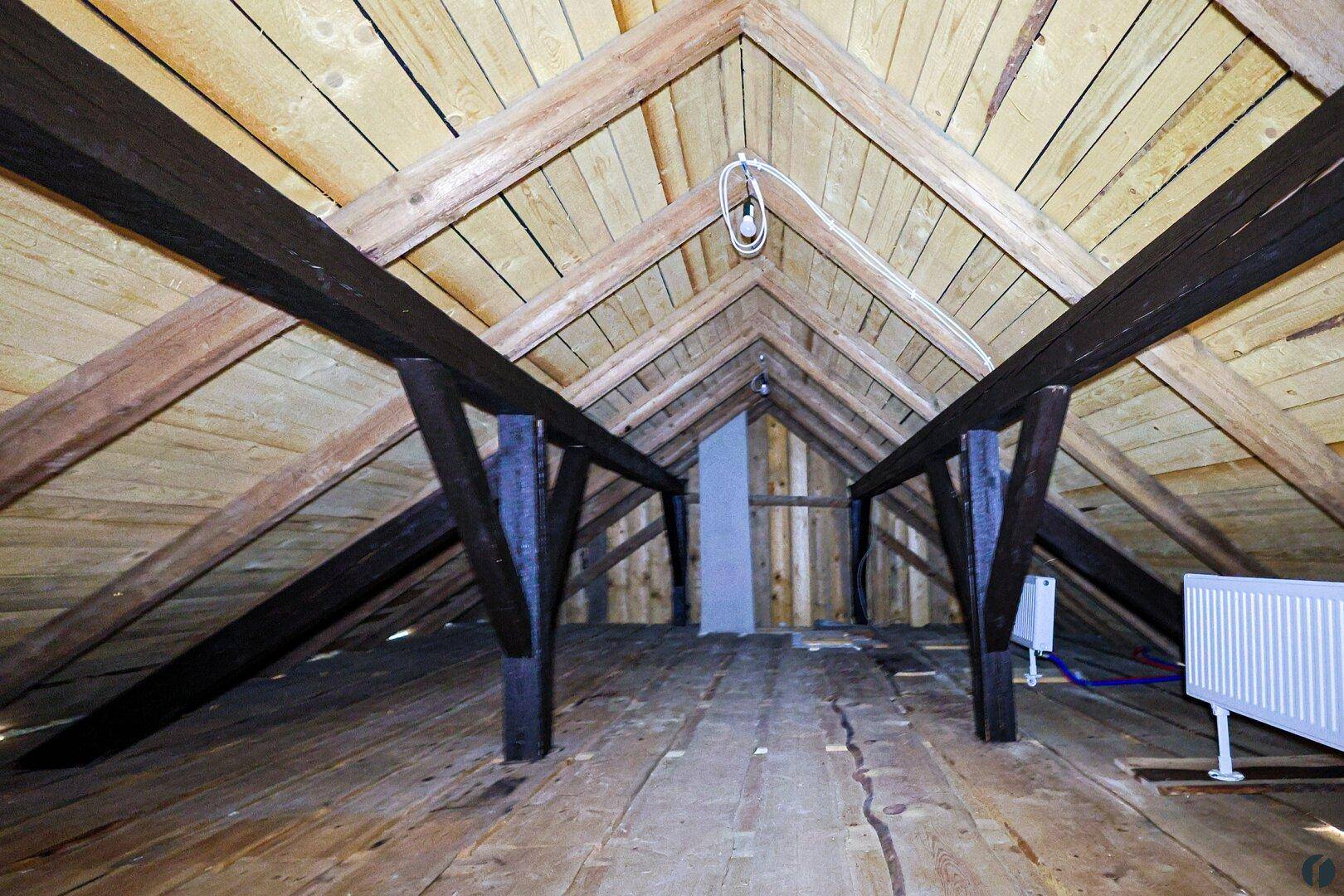 Geräumiger Dachboden mit sichtbaren Holzbalken und Dielenboden, bereit für den Ausbau.