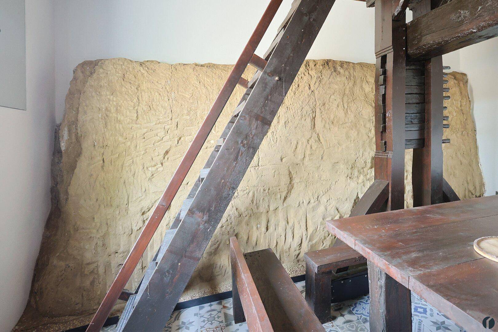 Rustikale Wandgestaltung mit Naturstein und einer Holztreppe, die zu einer oberen Ebene führt.