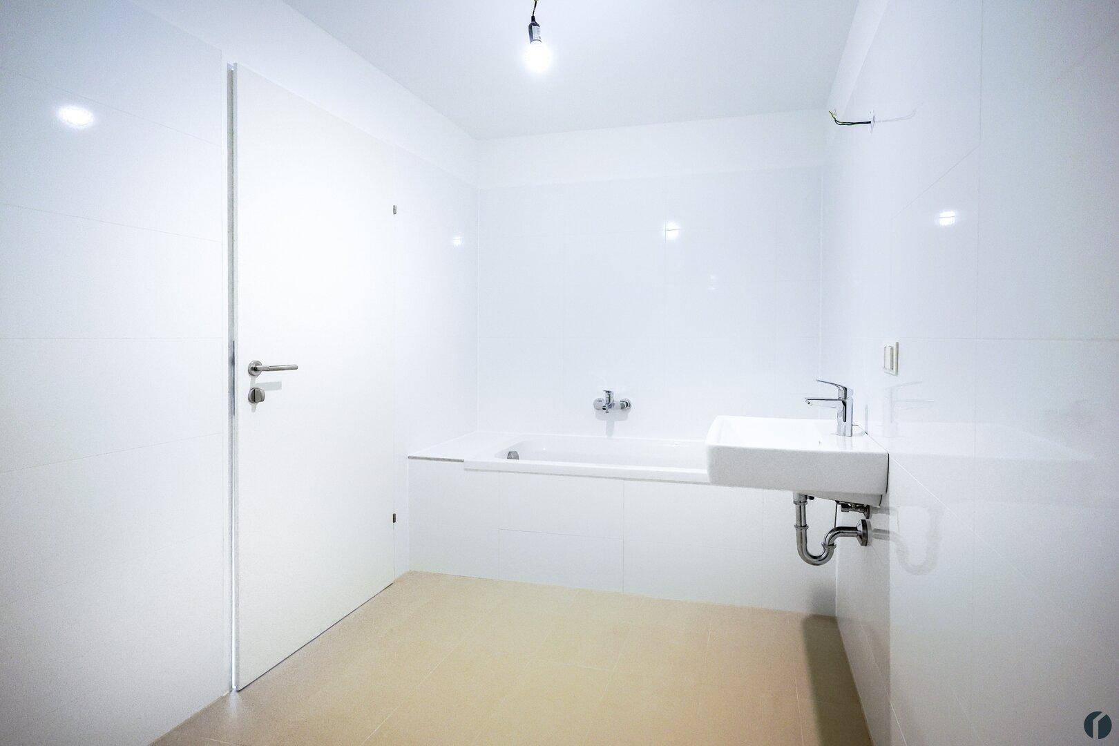 Modernes Badezimmer mit Badewanne, Waschbecken und weißen Fliesen.
