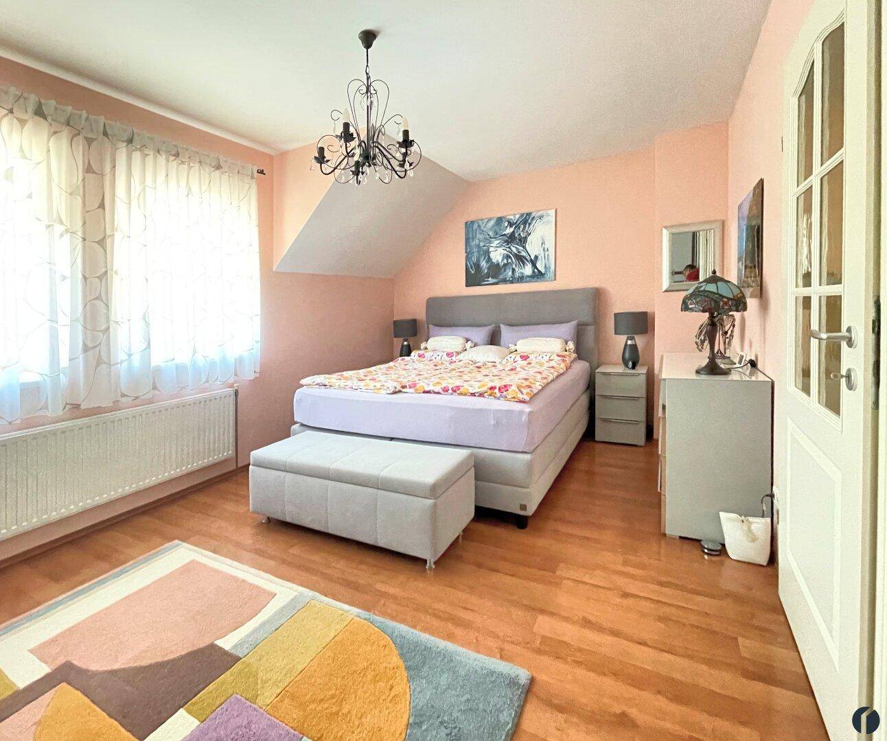 Gemütliches Schlafzimmer mit großem Bett, Holzboden und Dachschräge, hell und einladend.