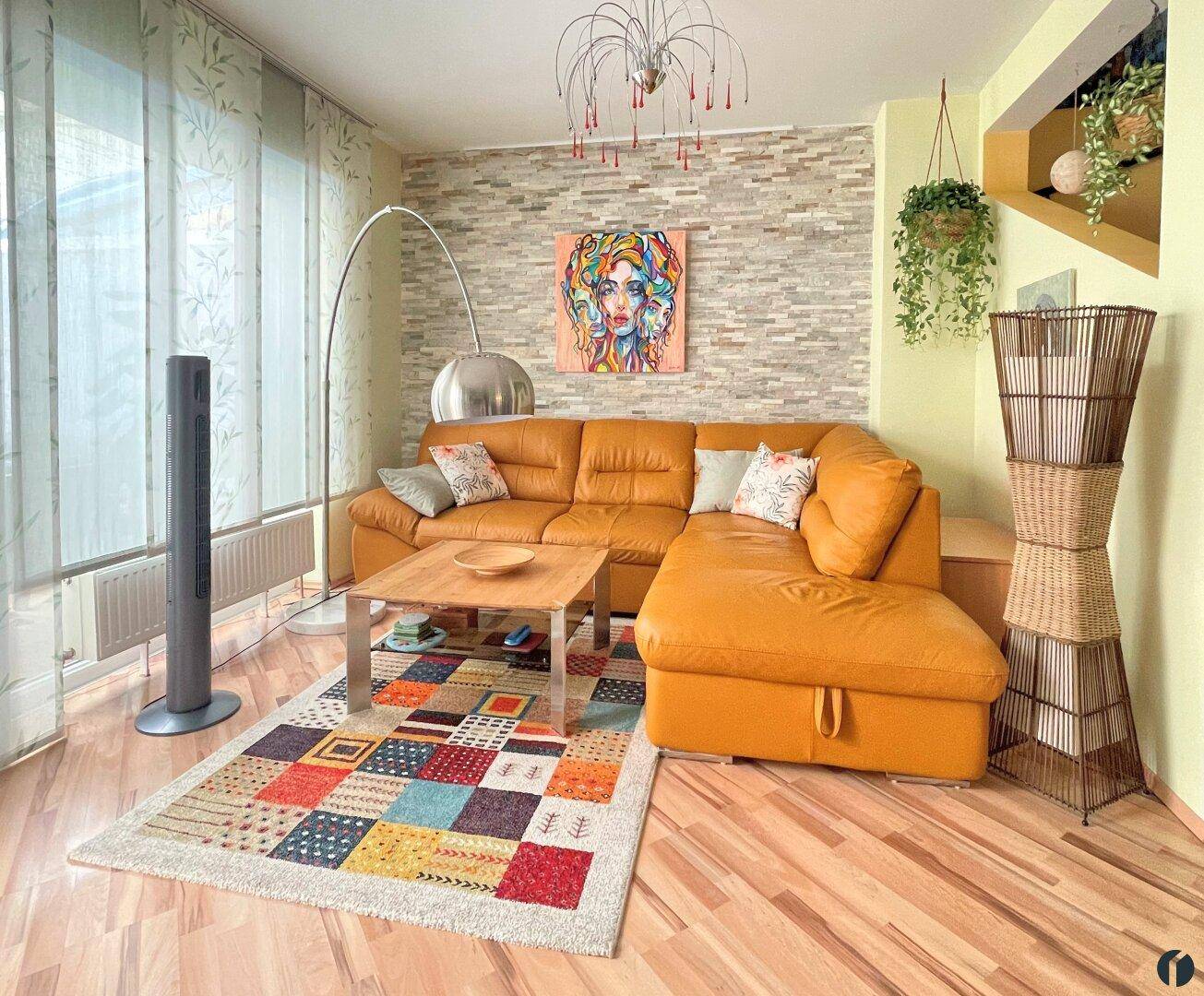 Wohnzimmer mit beiger Ledercouch, dekorativer Steinwand und modernem Bogenlampen-Design.
