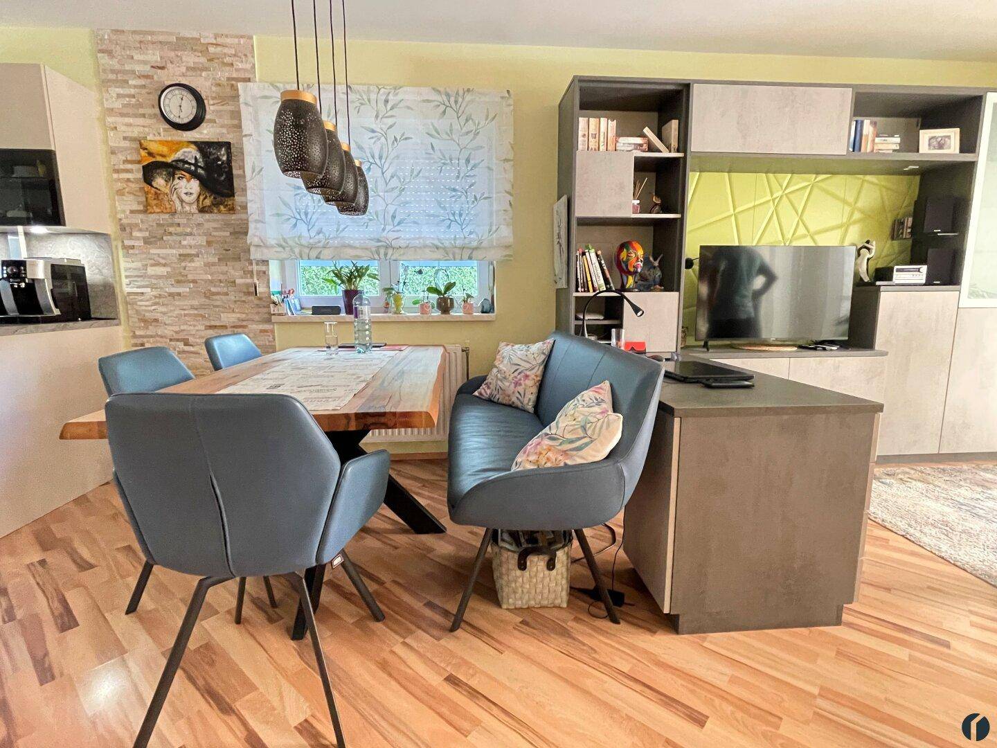 Offener Essbereich mit großem Holztisch, modernen Stühlen und Blick auf den Wohnbereich.