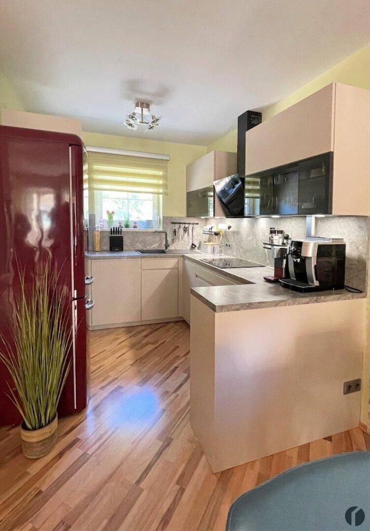 Helle Küche mit modernen Schränken, retro-rotem Kühlschrank und Holzboden.